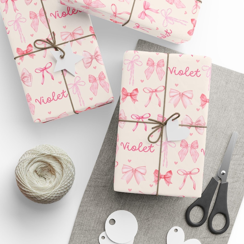 Girly wrapping paper with repeating pink bows, pink hearts, and customized with a name. Coquette birthday supplies, pink bow party supplies, girly birthday theme.