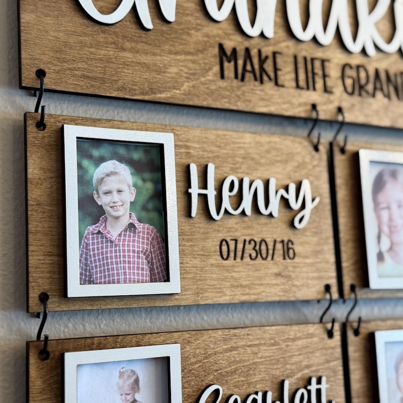 Op de afbeelding: Houten fotodisplay voor het gezin met de woorden "Make Life Grand" in witte letters. Het display bevat individuele fotolijsten, de naam "Henry" in witte letters en de datum "07/30/16". Het hout heeft een warme, natuurlijke afwerking.