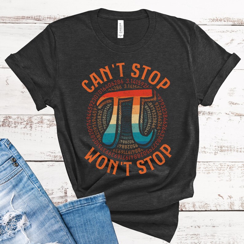 May include: A dark gray t-shirt with a vintage-style graphic of the mathematical constant pi. The graphic features a rainbow color scheme and the text "CAN'T STOP WON'T STOP".