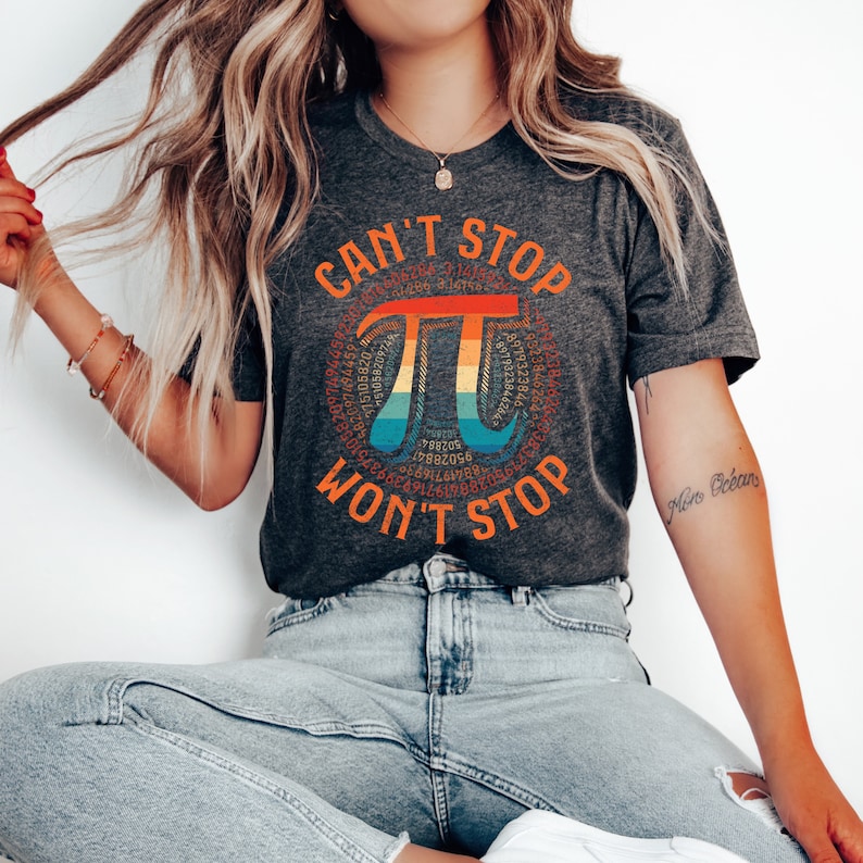 May include: A dark gray t-shirt with a rainbow colored pi symbol surrounded by the digits of pi. The text "Can't Stop Pi Won't Stop" is written in a circle around the pi symbol.
