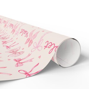 May include: Pink wrapping paper with a repeating pattern of pink bows and the word "Sister" in pink script.