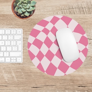May include: A round pink and white checkered mousepad with a white computer mouse on a wooden desk. A white keyboard and a small potted succulent are also visible.