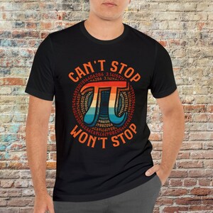 May include: A black t-shirt with a graphic design featuring the mathematical constant pi. The graphic is a circle with the digits of pi arranged in a spiral pattern. The text "CAN'T STOP" and "WON'T STOP" are written above and below the circle, respectively.