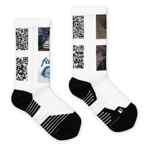 Könnte beinhalten: Weiße Sportsocken mit schwarzen Akzenten an Ferse und Zehen. Die Socken zeigen mehrere QR-Codes und kleine Bilder, darunter das Wort "fit" und ein Kompass-Design. Die Socken sind für sportliche Aktivitäten konzipiert.