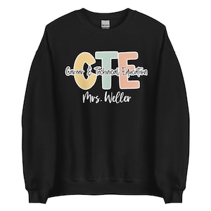 Könnte beinhalten: Schwarzes Sweatshirt mit dem Text "CTE Career & Technical Education Mrs. Weller" in einem farbenfrohen Design. Die Buchstaben "CTE" sind in Pastellfarben: Gelb, Türkis und Pfirsich. Der Text ist in einem lässigen, handschriftlichen Stil gehalten.