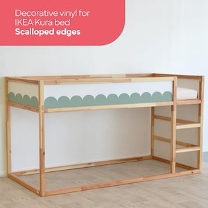 Op de afbeelding: Een houten IKEA Kura bedframe met een witte en groene vinyl sticker met een gegolfde rand. Het bedframe staat in de lage stand en heeft een ladder aan de zijkant.