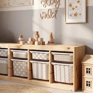 Könnte beinhalten: Holzaufbewahrungseinheit mit gemusterten Behältern und Holzspielzeug. Die Behälter weisen florale, gestreifte und karierte Designs in neutralen Tönen auf. Holzblöcke, ein Stapelturm und ein kleines Holzhaus sind ebenfalls zu sehen.