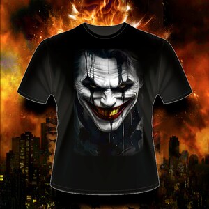 May include: Black t-shirt with a graphic print of the Joker's face. The Joker is smiling with a wide, toothy grin. His face is painted white with black and red accents.