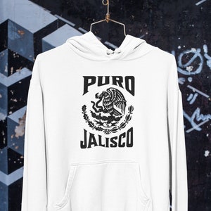 Op de afbeelding: Witte hoodie met een zwarte afbeelding van het Mexicaanse wapenschild en de tekst "PURO JALISCO".