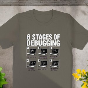 T-shirt with "6 Stages of Debugging" text and six laptop graphics illustrating programming stages.