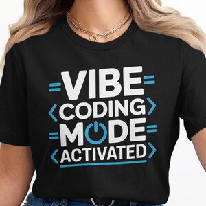 Black t-shirt with "VIBE CODING MODE ACTIVATED" text in blue and white.