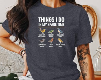 May include: A dark blue t-shirt with the text "Things I do in my spare time" and a graphic of six different birds with text describing what the person does with the birds. The text includes "Hang out with birds", "Look at birds", "Research birds", "Talk about birds", "Feed birds", and "Dream about birds".