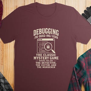 Maroon t-shirt with text "Debugging: The Classic Mystery Game".