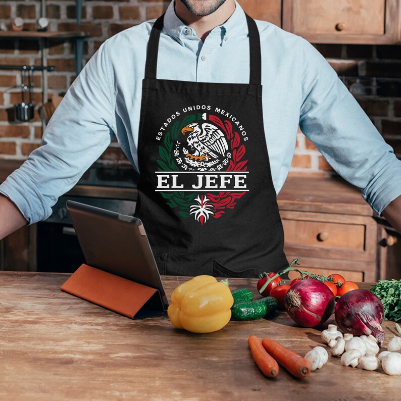 May include: Black apron with a white circle design featuring the Mexican coat of arms with an eagle and the text "Estados Unidos Mexicanos" and "El Jefe".