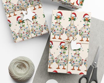 May include: Wrapped gifts with a festive goose pattern. The geese are wearing Santa hats and wrapped in Christmas lights. The gifts are tied with twine and adorned with white tags. A spool of twine and scissors are also visible.