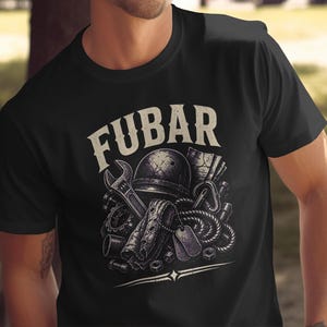 Puede incluir: Una camiseta negra con un estampado gráfico que incluye el texto FUBAR en una fuente desgastada. La ilustración muestra un casco militar, una llave inglesa, una cuerda enrollada, placas de identificación y varios componentes mecánicos.