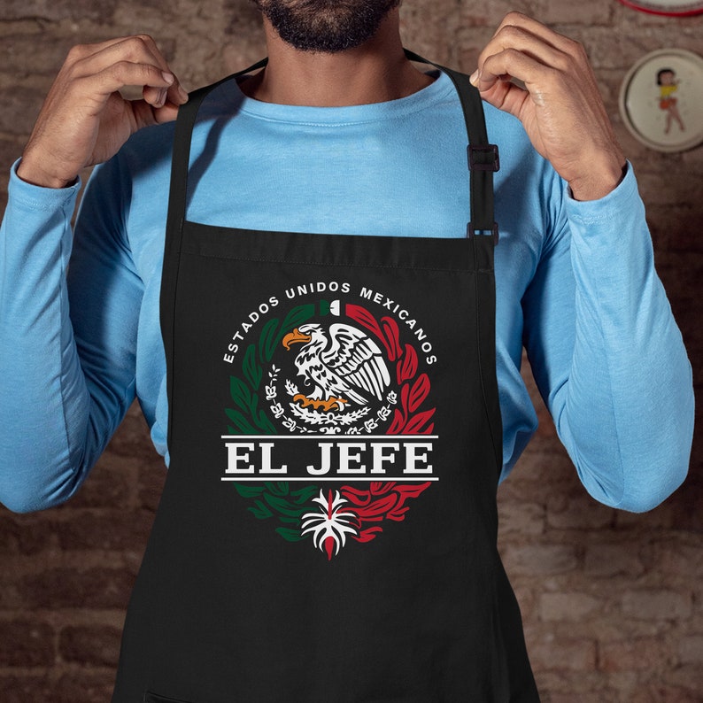 May include: Black apron featuring a green, white and red Mexican flag design. The text "ESTADOS UNIDOS MEXICANOS" is written in a circle around the flag. The text "EL JEFE" is written below the flag.