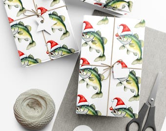 May include: Wrapping paper featuring a repeating pattern of green bass fish wearing red and white Santa hats, with some fish holding small red ornaments. The paper is tied with brown twine and includes white star and heart-shaped gift tags.