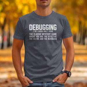 Dark grey t-shirt with white text defining "Debugging" as a classic mystery game.