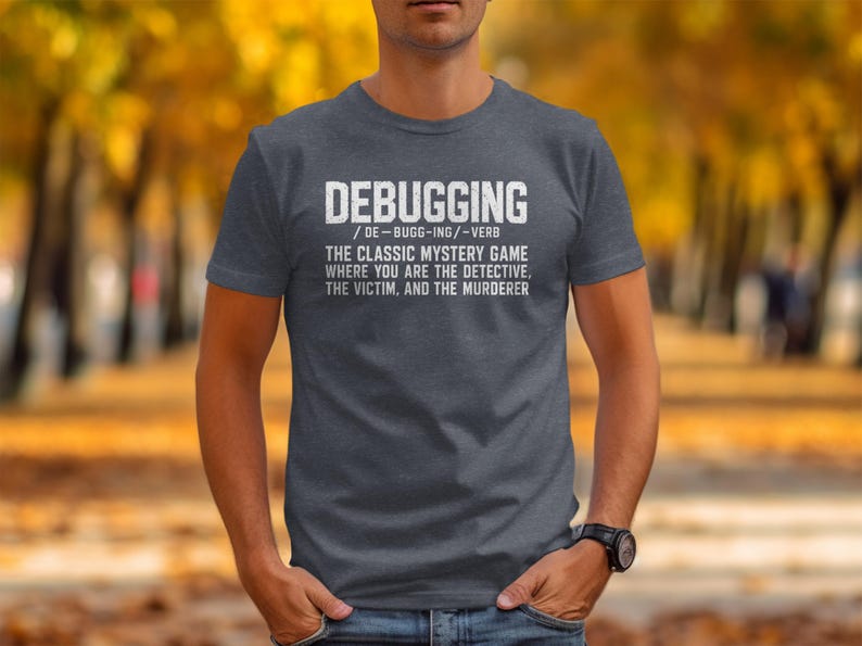 Dark grey t-shirt with white text defining "Debugging" as a classic mystery game.