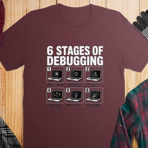 Burgundy t-shirt with "6 Stages of Debugging" text and humorous graphics.