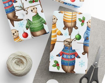 May include: Gift wrap featuring otters in colorful sweaters, snowflakes, and ornaments. The wrapping paper is tied with twine and a blank tag. A ball of twine, scissors, and blank tags are also visible.