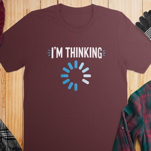 Maroon t-shirt with "I'M THINKING" and a blue loading icon.
