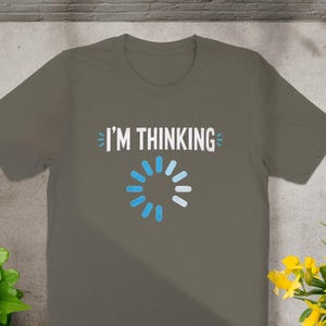 Grey t-shirt with white text "I'M THINKING" and a blue loading circle.