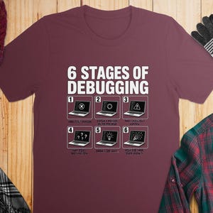 Maroon t-shirt with "6 Stages of Debugging" and six humorous programming stages.