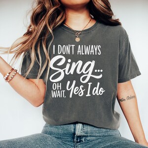 May include: A charcoal gray short-sleeve t-shirt featuring white text that reads I DON'T ALWAYS Sing... OH WAIT, Yes I do. The shirt has a crew neckline and a relaxed fit, with the graphic printed in a combination of block and script fonts.