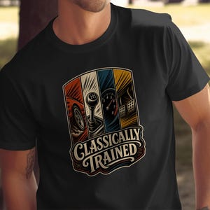 以下が含まれることがあります： 「CLASSICALLY TRAINED」という文字がプリントされた黒の半袖Tシャツ。グラフィックには、車のホイール、マニュアルシフトレバー、スピードメーター、フットペダルの4つの垂直パネルが赤、白、青、黄の色調で描かれています。