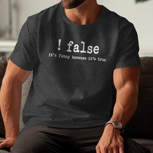 Dark gray t-shirt with white text "! false it's funny because it's true".