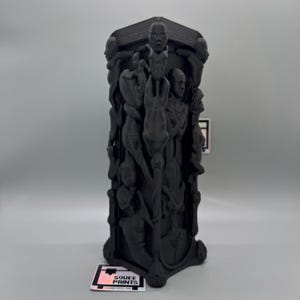 May include: A black 3D printed sculpture of a group of figures trapped inside a rectangular frame. The figures are contorted and appear to be in distress. The sculpture is a dark and eerie piece of art.