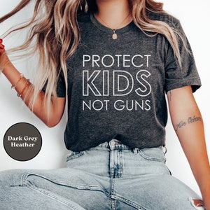 May include: A dark grey heather t-shirt with the text "PROTECT KIDS NOT GUNS" printed in white.