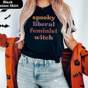 May include: Black unisex t-shirt with the text "spooky liberal feminist witch" in colorful lettering.