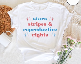 May include: White t-shirt with the text "stars stripes & reproductive rights" in blue and red lettering with stars around the text.