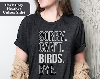 May include: A dark grey heather unisex t-shirt with the text "SORRY. CAN'T. BIRDS. BYE." printed in white.