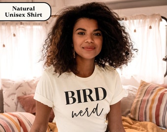 May include: A white unisex t-shirt with the text "BIRD nerd" printed in black.