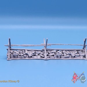 May include: A gray miniature model of a stone wall with a wooden fence structure on top. The model features a textured base of stacked stones and vertical wooden posts with horizontal rails. The text "Designed by Gordon Kitney" and "BATTLE HONOURS 3D" is visible.
