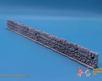 Puede incluir: Un modelo de muro de piedra gris, largo y recto, con una superficie rocosa texturizada e irregular y una base plana. El texto "Designed By Gordon Kitney" aparece en la parte inferior izquierda, y "BATTLE HONOURS 3D" con un icono de bandera a la derecha.