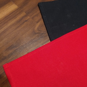 May include: Two fabric placemats, one red and one black, are laid out on a wooden surface.