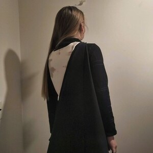 May include: A black long-sleeved dress with a white and brown patterned back.