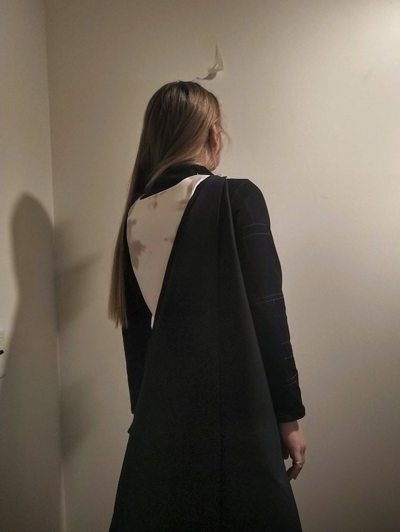 May include: A black long-sleeved dress with a white and brown patterned back.