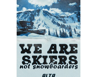 May include: A vintage poster with a blue and white image of a snowy mountain scene with a ski lift and the text "WE ARE SKIERS not snowboarders" and the word "ALTA" at the bottom.