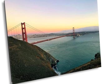 May include: A scenic photograph of the Golden Gate Bridge in San Francisco, California. The iconic red bridge spans across the water, with a city skyline in the background. The sky transitions from orange to blue.