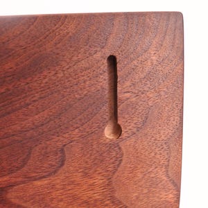 May include: Close-up of a wooden plaque with a dark brown finish. The wood grain is visible. A vertical keyhole slot is carved into the wood, with a circular opening at the bottom. The plaque is likely for wall mounting.
