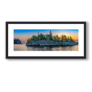 Puede incluir: Fotografía panorámica enmarcada de una isla escénica al atardecer. La isla está cubierta de árboles verdes y se encuentra en una masa de agua. El cielo hace la transición de azul a naranja y amarillo.