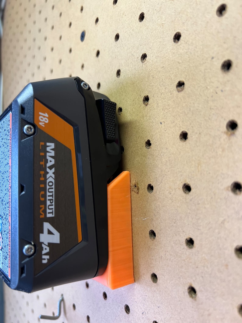 Puede incluir: Un soporte de bater&iacute;a de pl&aacute;stico naranja para una bater&iacute;a de litio negra y naranja de 18v MAX OUTPUT 4Ah.