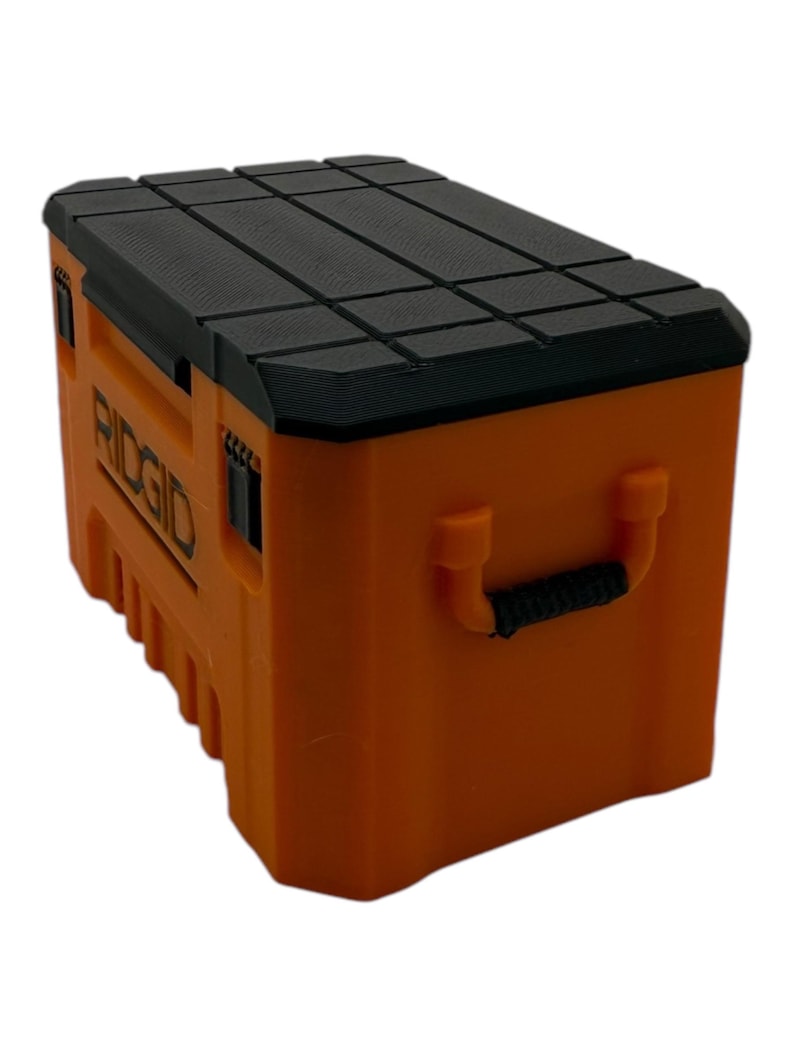 May include: An orange plastic tool box with a black lid and a black handle. The box has the word "RIDGID" printed on the side.