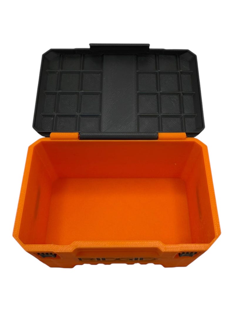 May include: An orange plastic storage box with a black lid. The lid has a grid of compartments for organizing small items.